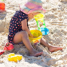 Girl playing with sand on a sand pit 